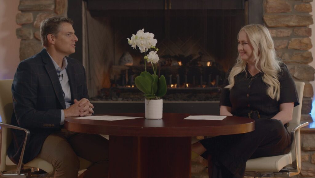 A Chamber Chats host speaks during an interview by the fireplace.