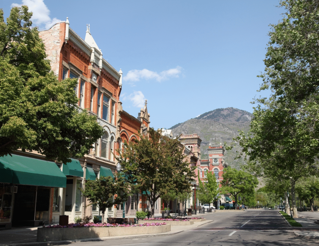 Historic downtown Provo street with red brick buildings and mountain backdrop.