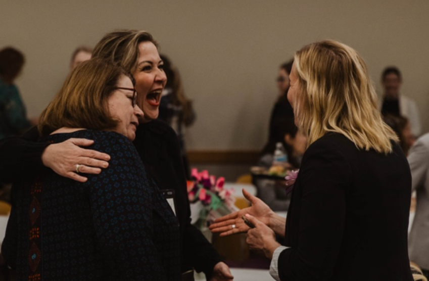 Women laughing and greeting each other at a Utah Valley Chamber networking event.